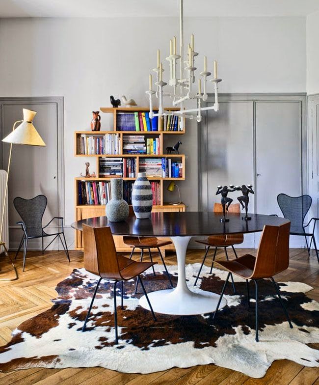 a dining room table with chairs and bookshelves in the background on a wooden floor