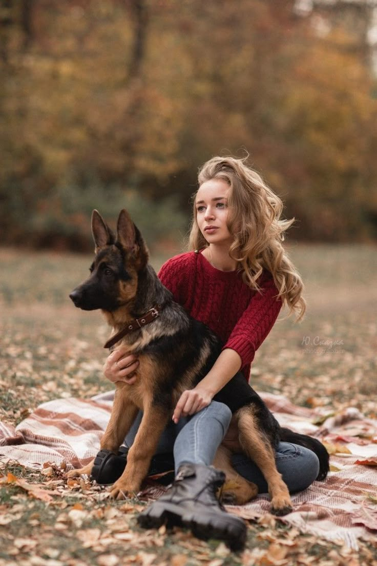 a woman sitting on top of a blanket holding a dog