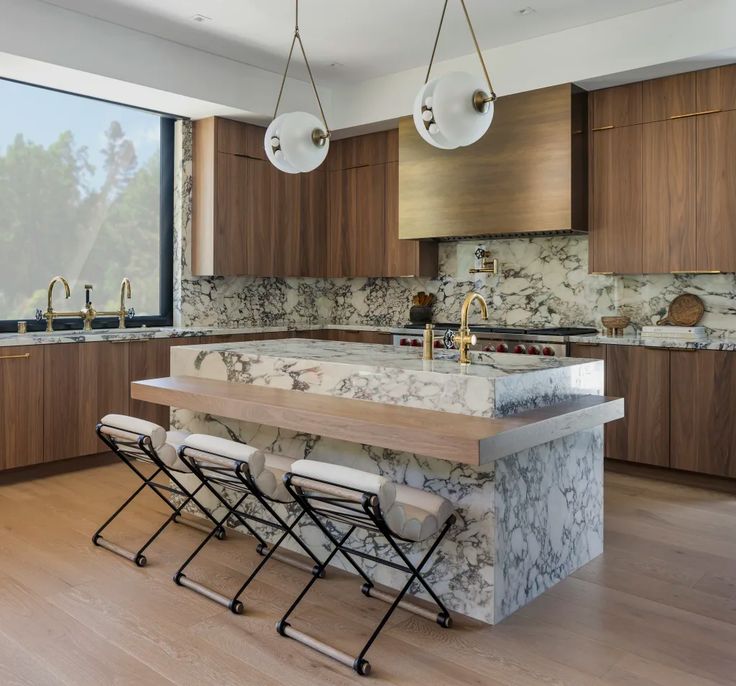 a large kitchen with marble counter tops and wooden cabinets, along with four bar stools