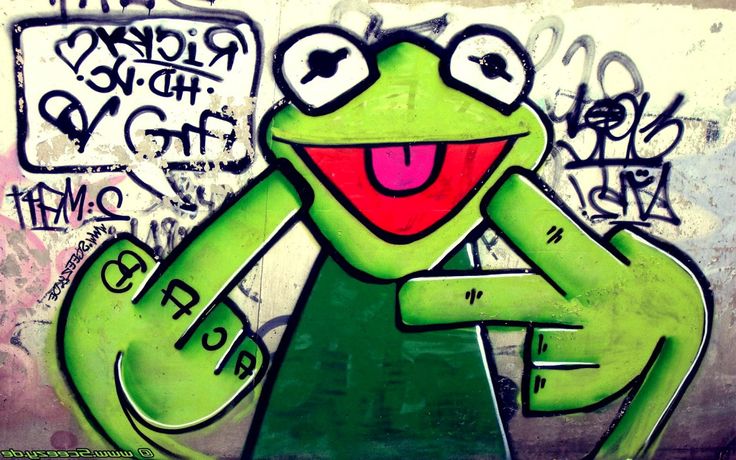 the frog is sitting in front of some graffiti