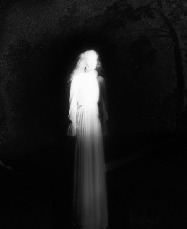 a ghostly woman standing in the dark