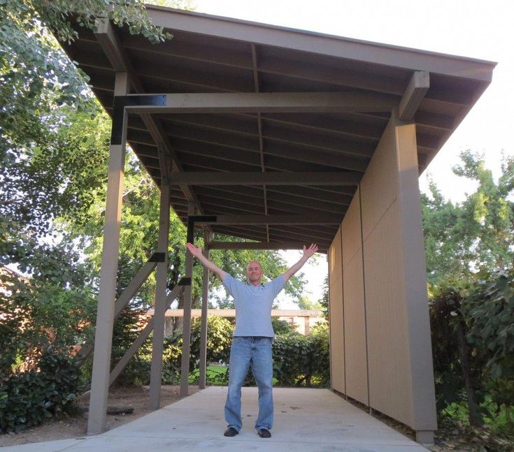 a man standing in front of a covered area with his arms up and hands raised