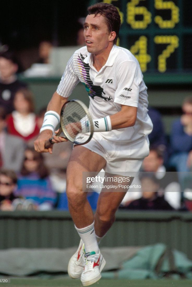 a man holding a tennis racquet on top of a tennis court in front of a crowd