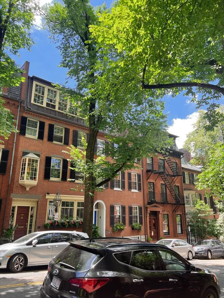 cars are parked on the street in front of some brick buildings with windows and balconies