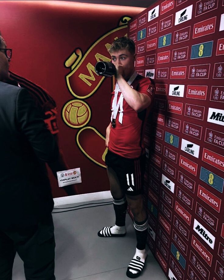 a man standing in front of a red wall holding a camera and taking a photo