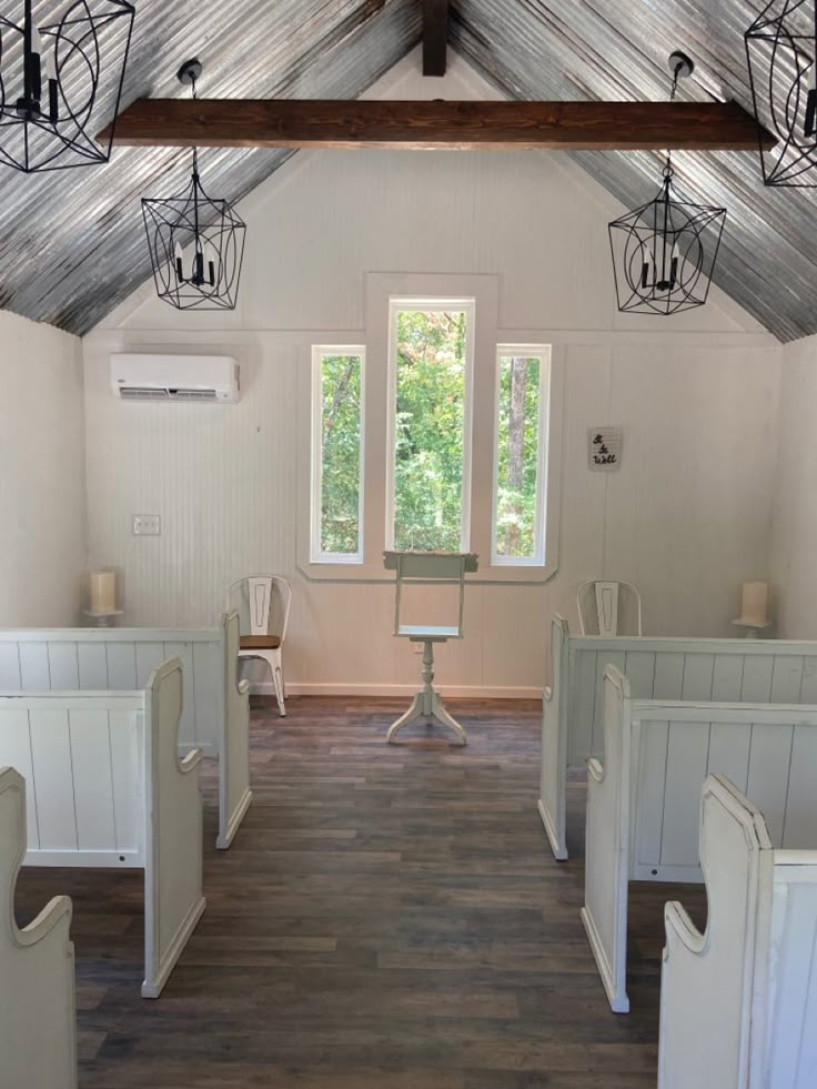 the inside of a small church with white pews and wood flooring is shown