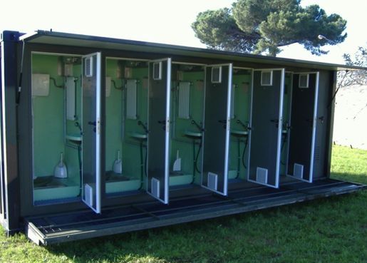 several portable toilets are lined up in the grass