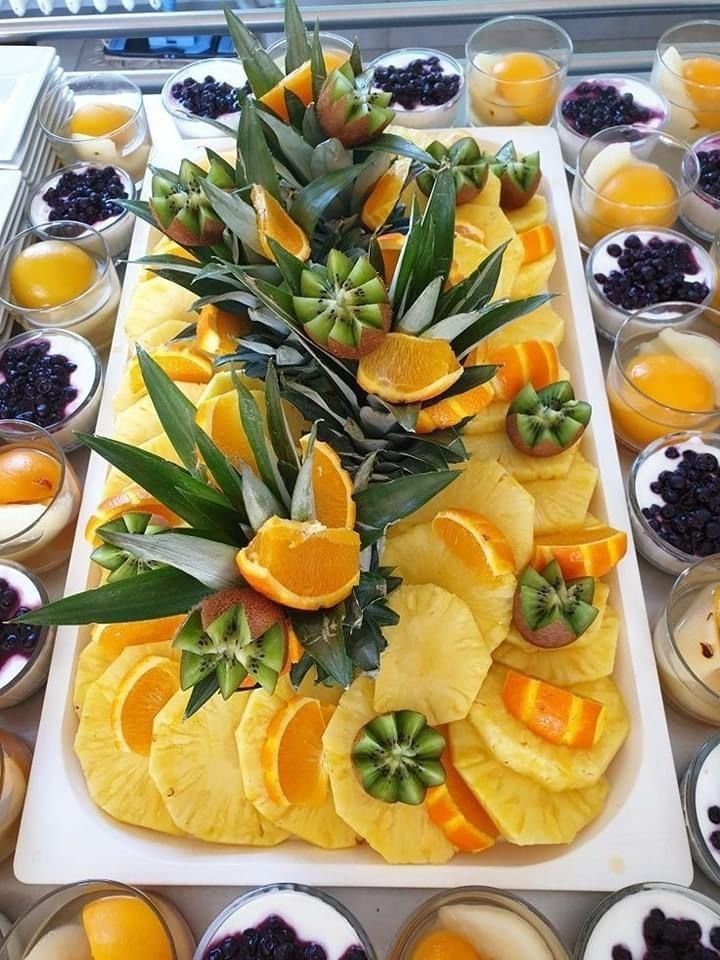 trays filled with different types of fruit and vegetables next to cups full of oranges