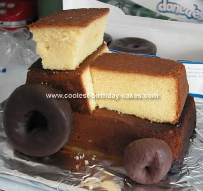 two pieces of cake sitting on top of foil with chocolate donuts in the background