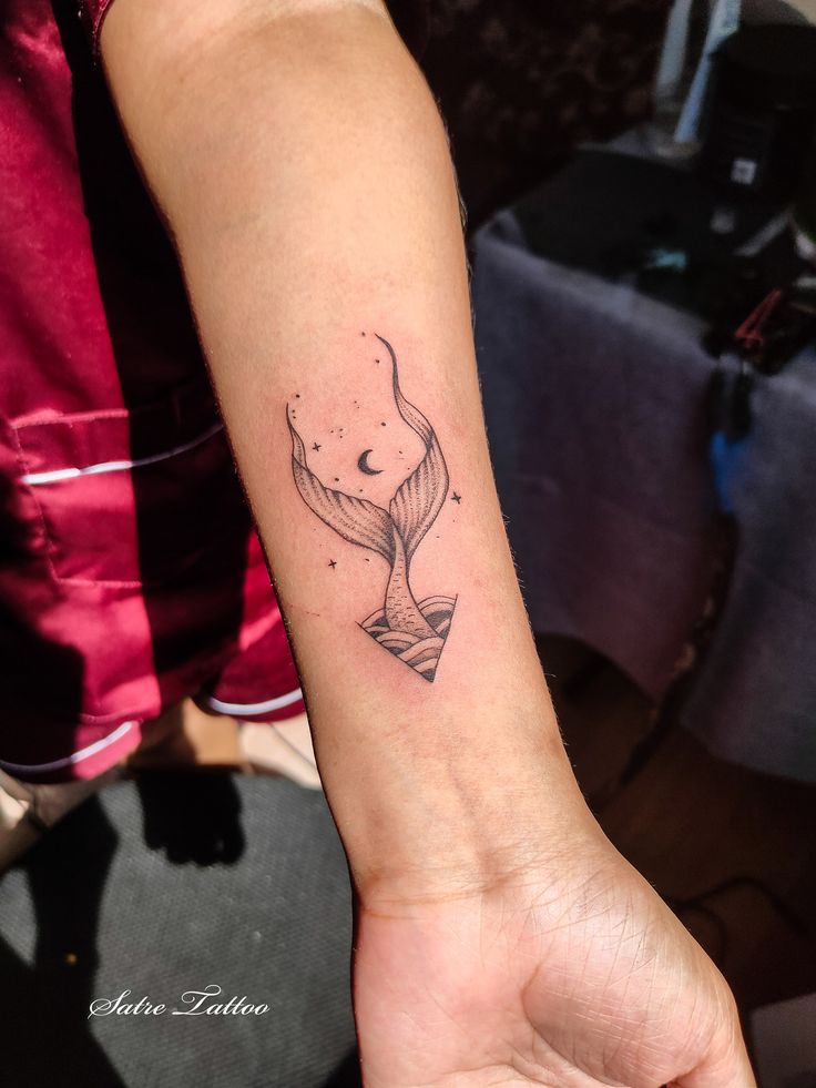 a woman's arm with a small whale tattoo on it