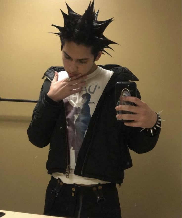 a man with spiked hair taking a selfie in front of a mirror holding a cell phone