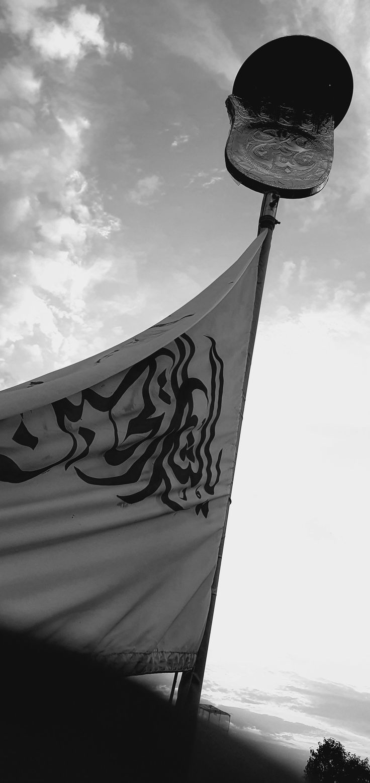 a black and white photo of a street light with a flag hanging from it's pole