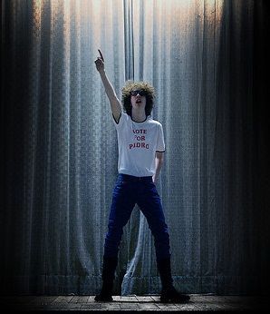 a man standing in front of a curtain with his hand up