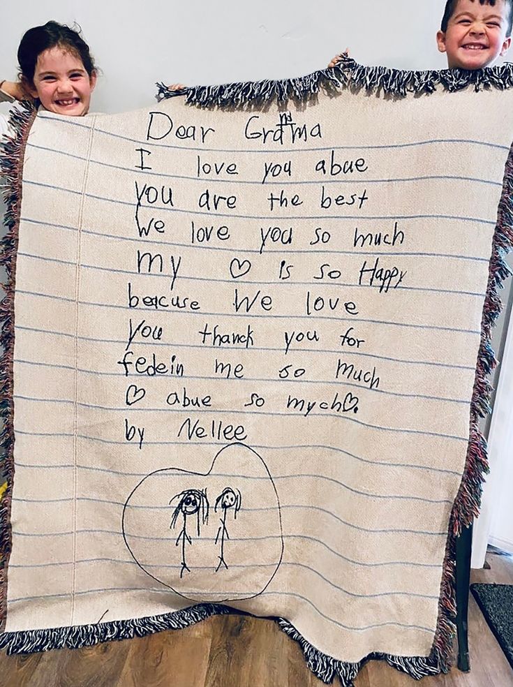 two children holding up a blanket with writing on it