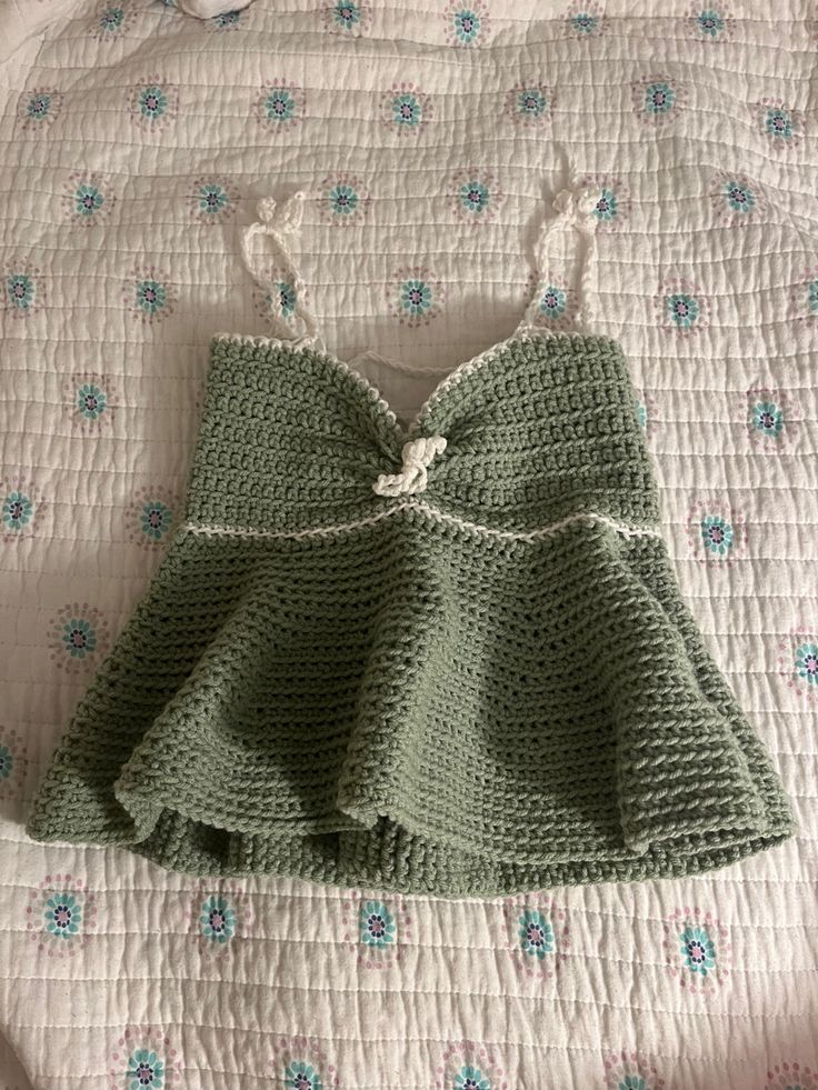 a crocheted green dress laying on top of a bed