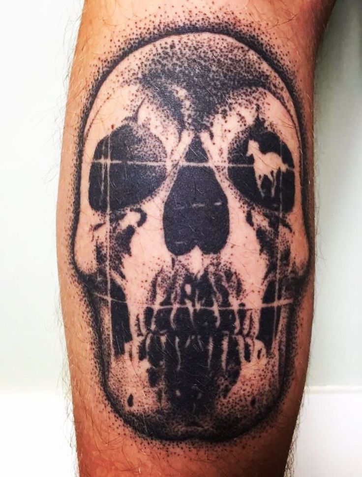 a man's leg with a skull tattoo on it and cross marks in the middle