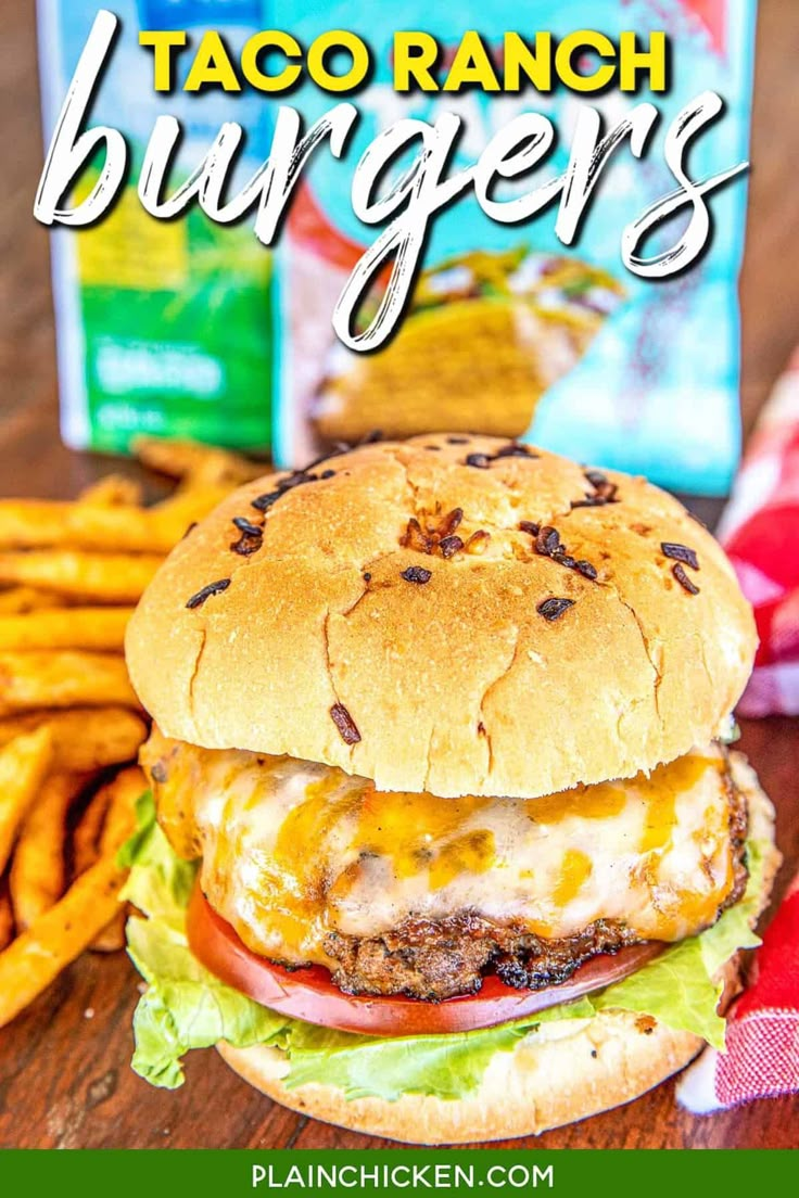 a hamburger with cheese and lettuce next to french fries on a wooden table