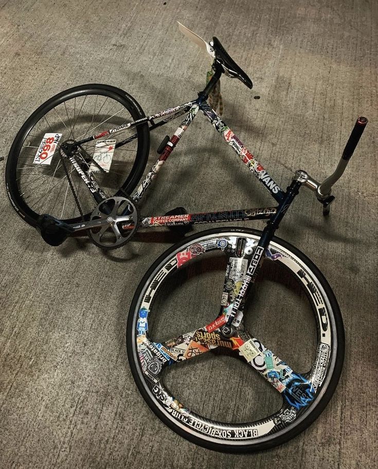 a bicycle with many stickers on it sitting on the floor next to a bike tire