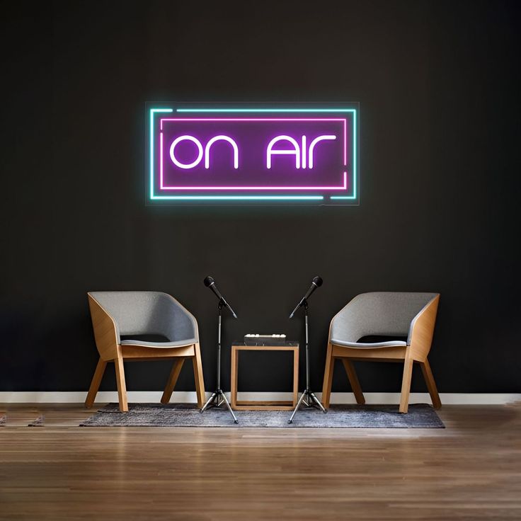 two chairs and a table in front of a neon sign that reads'on air '