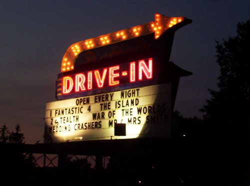 the drive - in sign is lit up at night