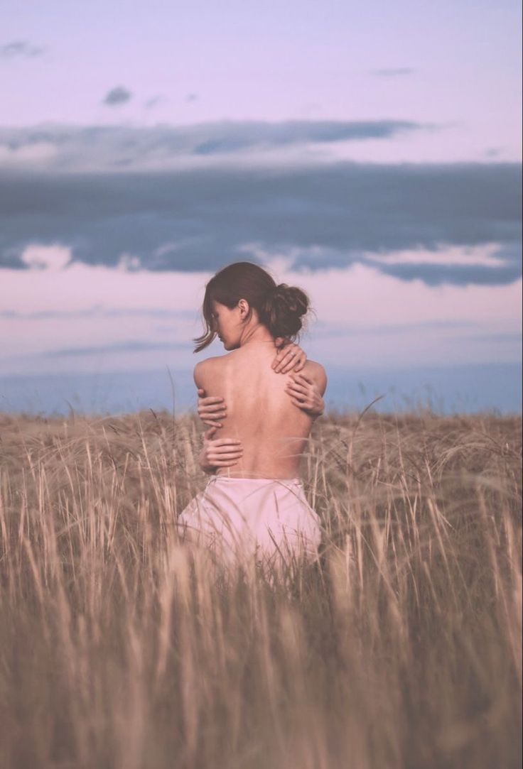 a woman standing in a field with her back to the camera