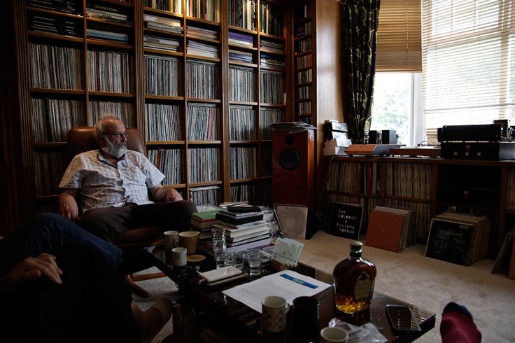 a man sitting in a chair next to a book shelf filled with books