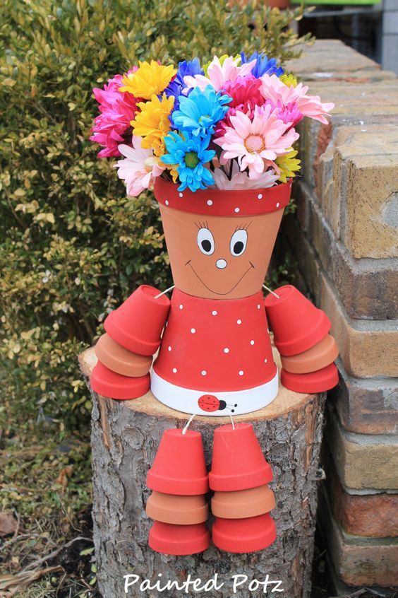 a flower pot sitting on top of a tree stump with flowers in it's mouth