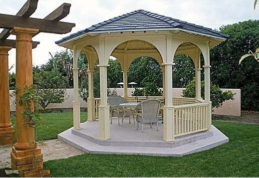 a white gazebo sitting on top of a lush green field