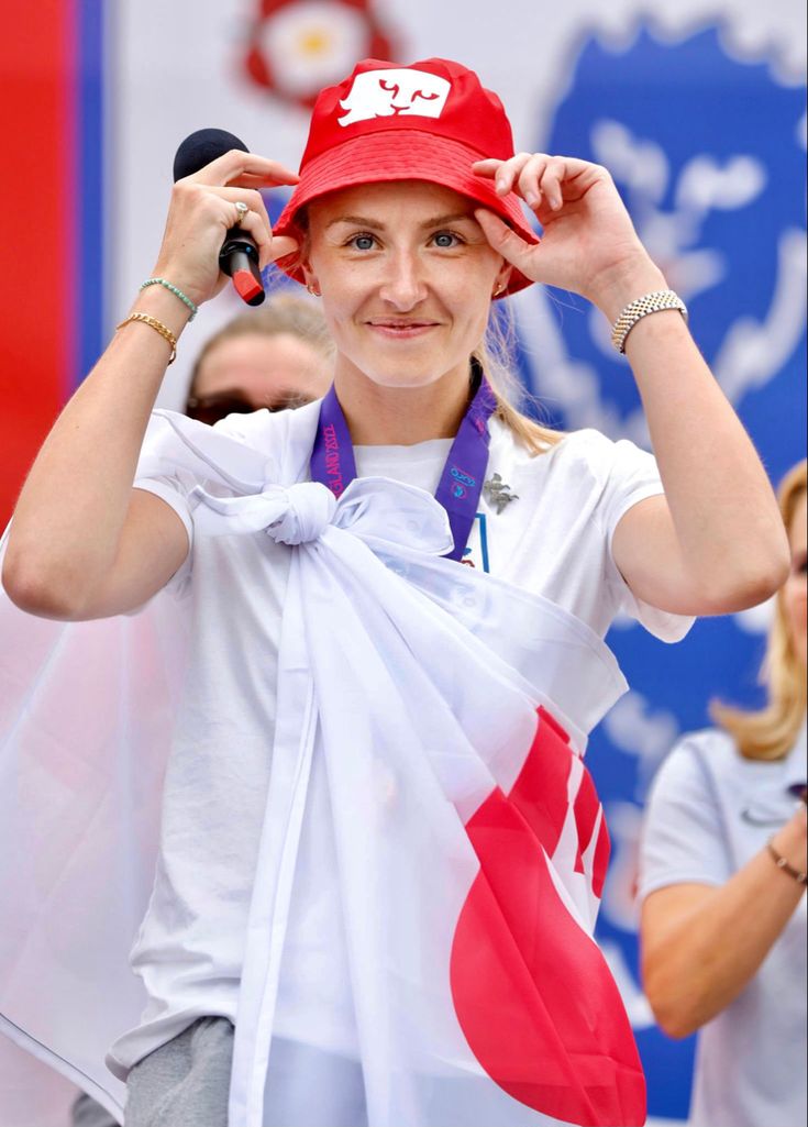 a woman wearing a red hat and white shirt holding a canadian flag in front of her face