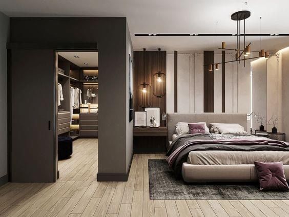 a bedroom with a large bed and closets in the back ground, surrounded by wooden flooring