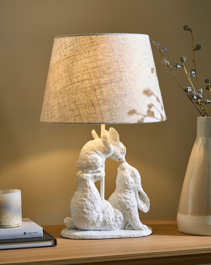 a lamp that is sitting on top of a table next to a vase with flowers