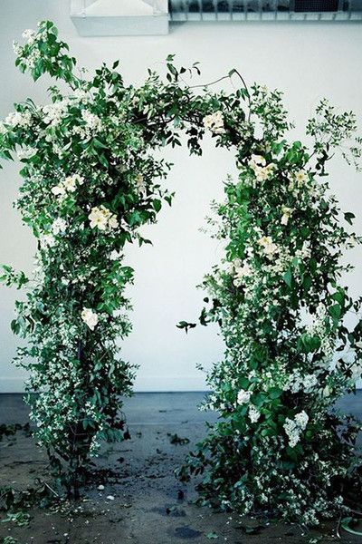 an arch covered in white flowers and greenery