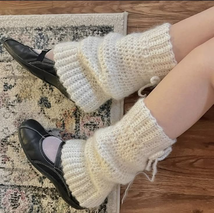 the legs of a woman wearing black shoes and white knitted socks, sitting on a rug