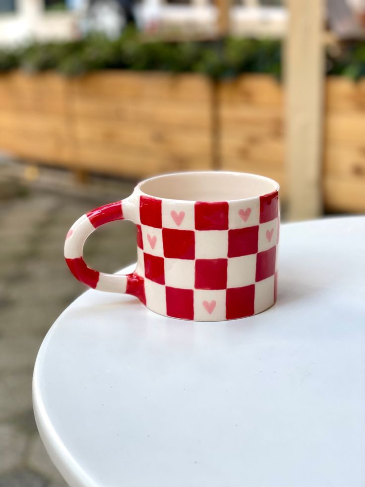 a red and white checkered coffee cup sitting on top of a table