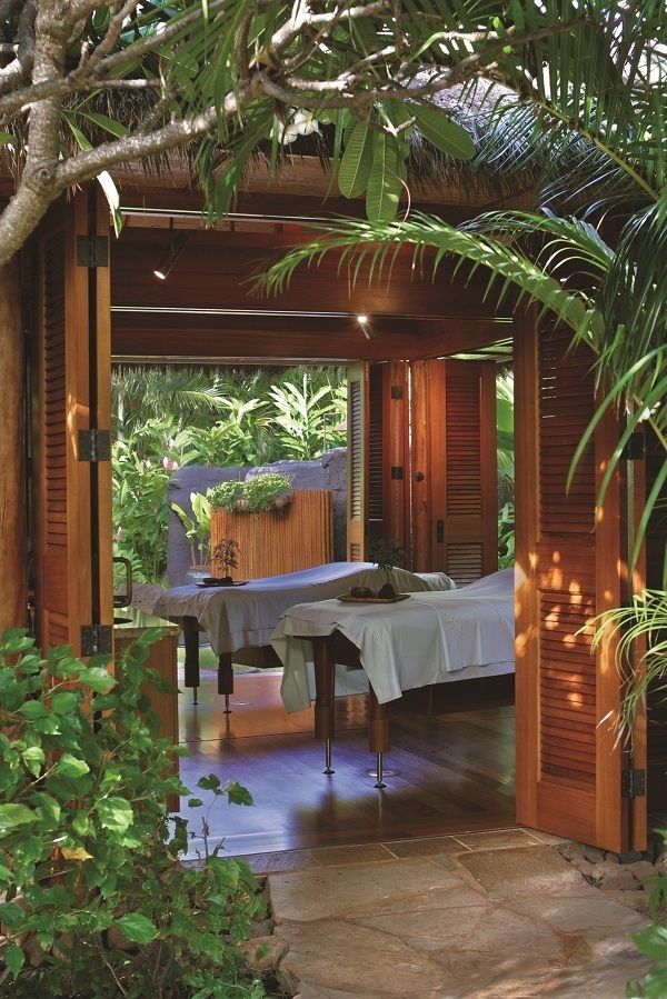 an outdoor dining area with table and chairs surrounded by greenery on either side of the patio