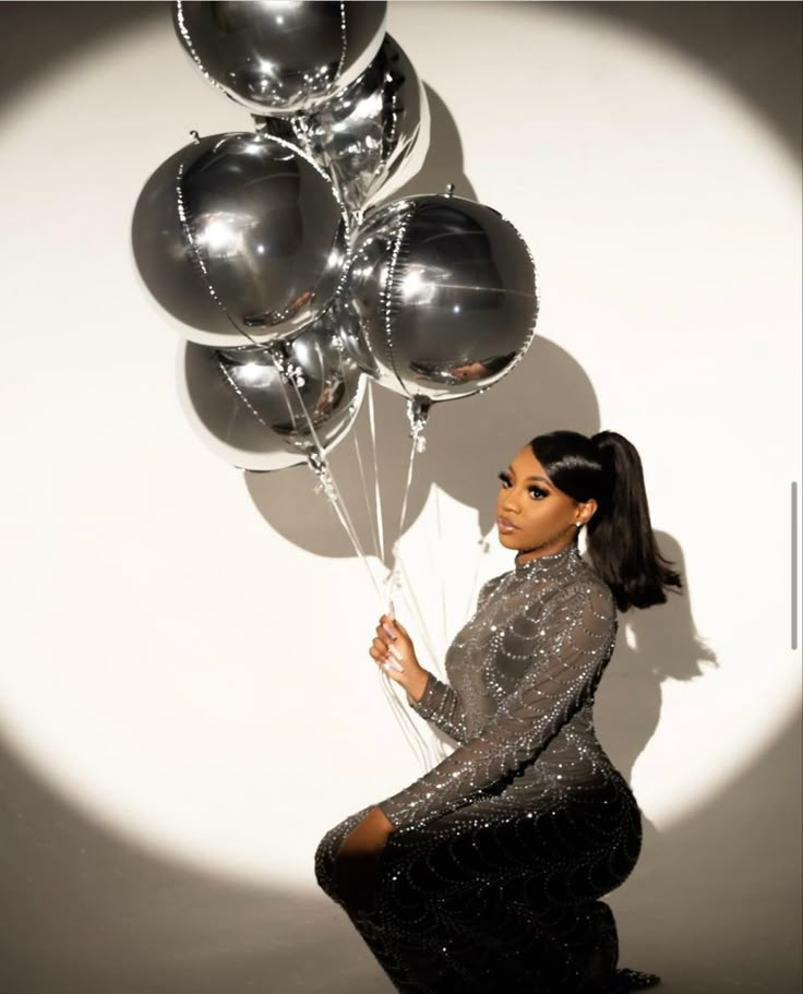 a woman holding some silver balloons in her hand