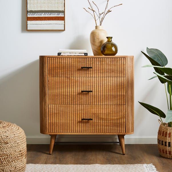 a wooden dresser sitting next to a potted plant on top of a hard wood floor