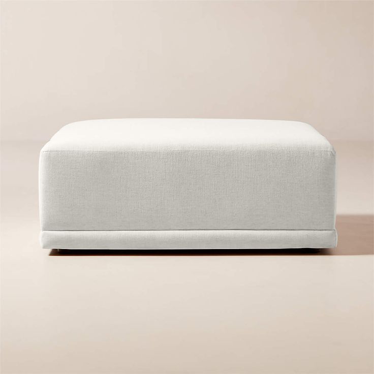 an upholstered footstool on a plain surface with no one in it