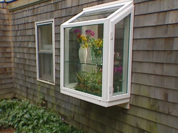 a white window sitting on the side of a house next to a green planter