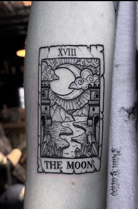 a tattoo on the arm of a person with a moon and castle in the background