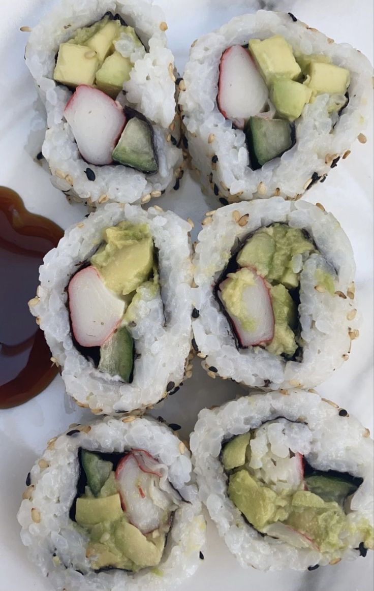 four sushi rolls with avocado, cucumber and sauce on the side