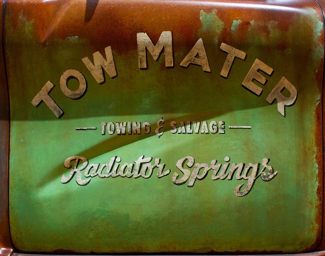 an old sign advertising tow matere towing and salvage, with rusted metal lettering