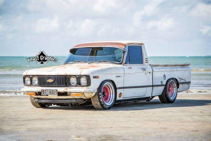 an old white truck parked on the beach