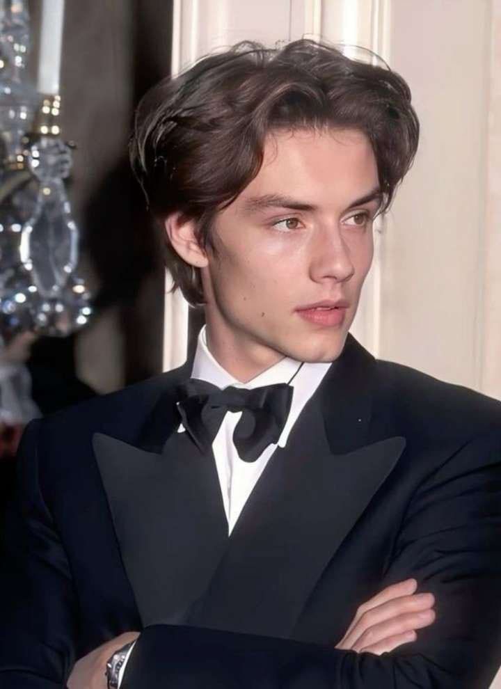 a young man in a tuxedo poses for the camera with his arms crossed