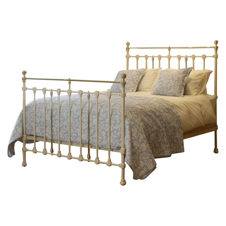 a metal bed frame with two pillows on top of it and a blanket over the headboard