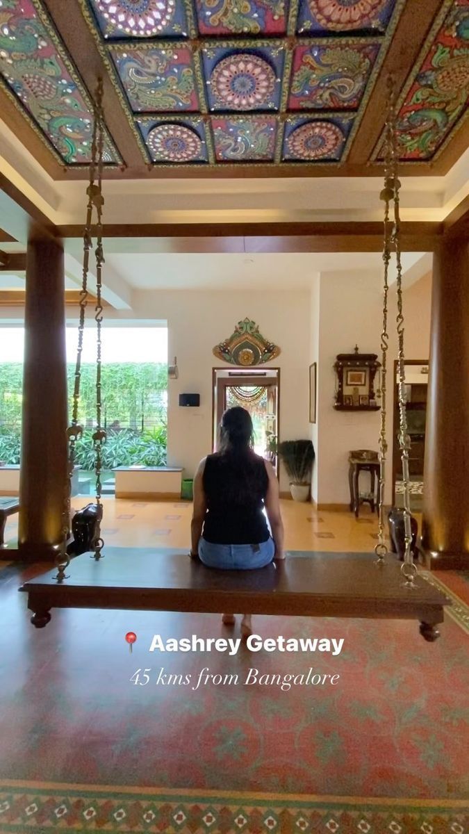 a woman sitting on a swing in the middle of a room with an ornate ceiling