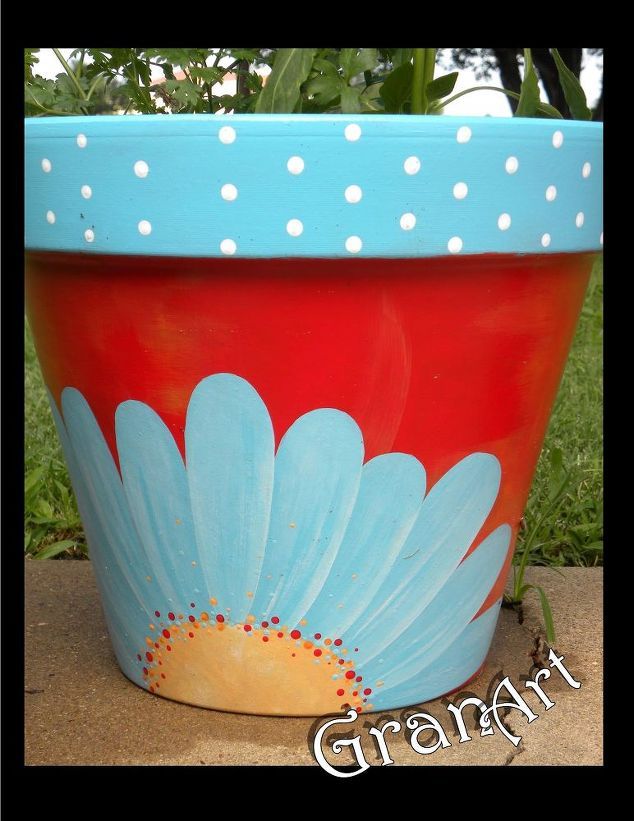 a painted flower pot sitting on top of a cement slab with grass in the background