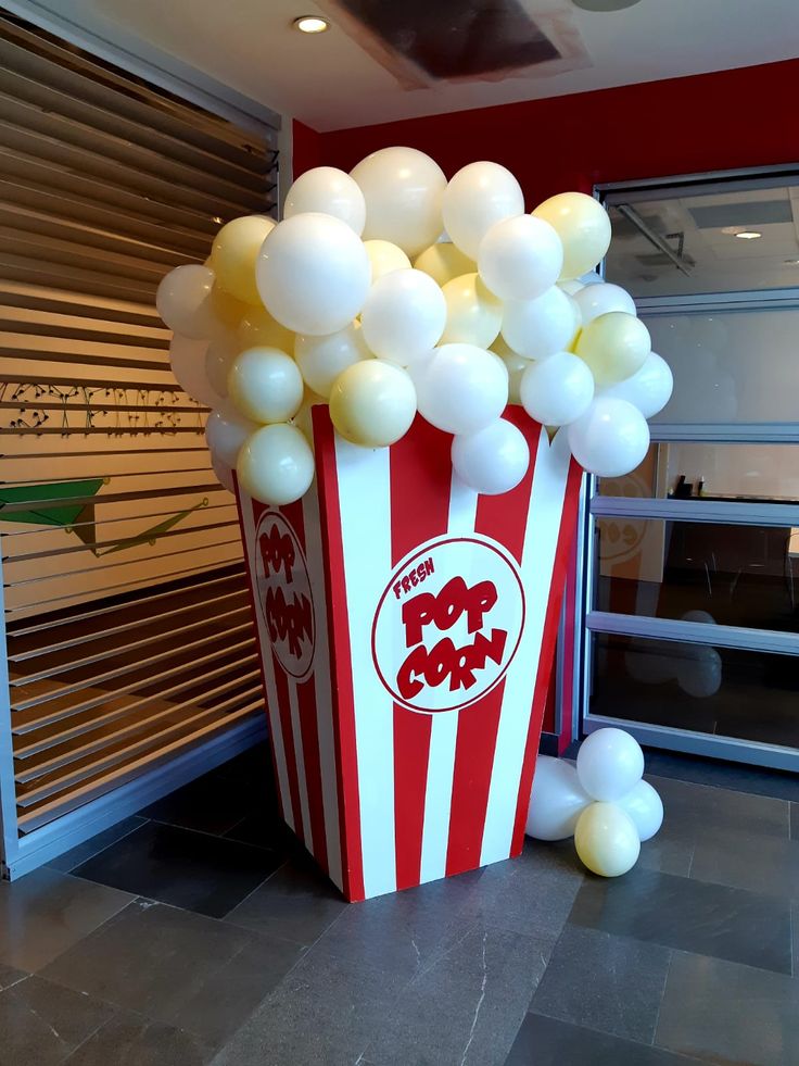 a popcorn box filled with white balloons sitting on top of a floor