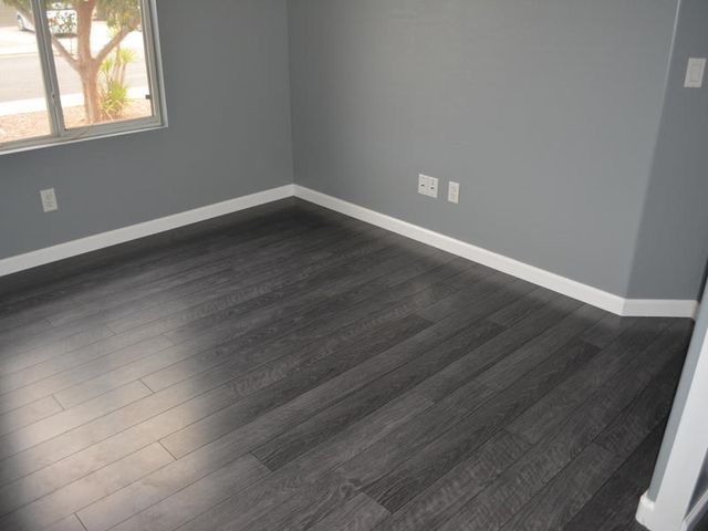 an empty room with gray walls and wood floors