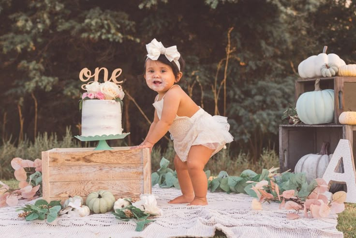 a baby girl standing in front of a cake